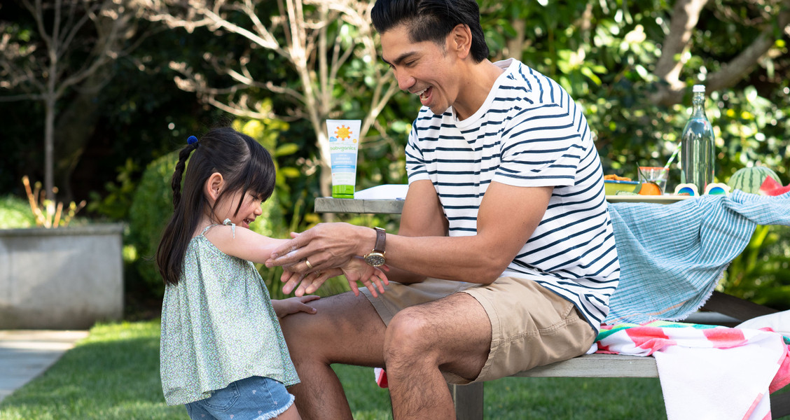 A man applying sunscreen to his daughter